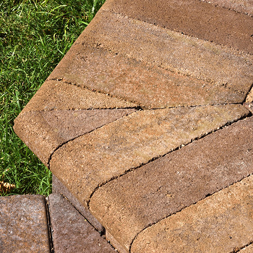 A close-up photo of bullnose pavers trimed to produce a 60º sharp corner of a patio step transithion in territorial corol blend