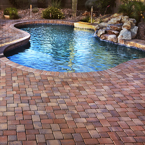 Photo of Veneer Pavers and pool coping in Tierra Norte color set on rounded form residential pool surround and patio in forground.